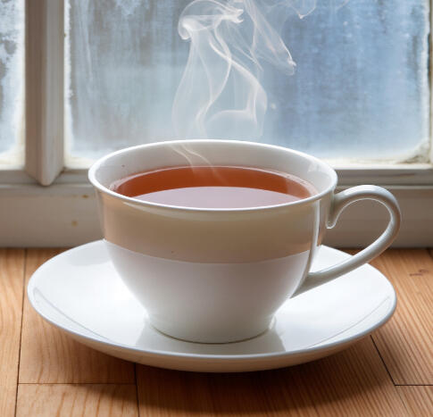 etabolic Stretching - 15 Minute Fat Burning Flow A young fit woman with hair in a ponytail performing a pigeon stretch on a black yoga mat in a bright home gym with plants.
